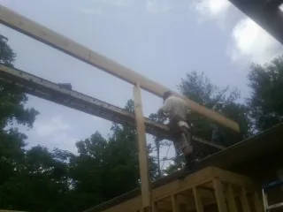 Carpenter setting a ridge beam over a new addition frame — Ice Dam Removal by Roofing Brothers in Lockwood