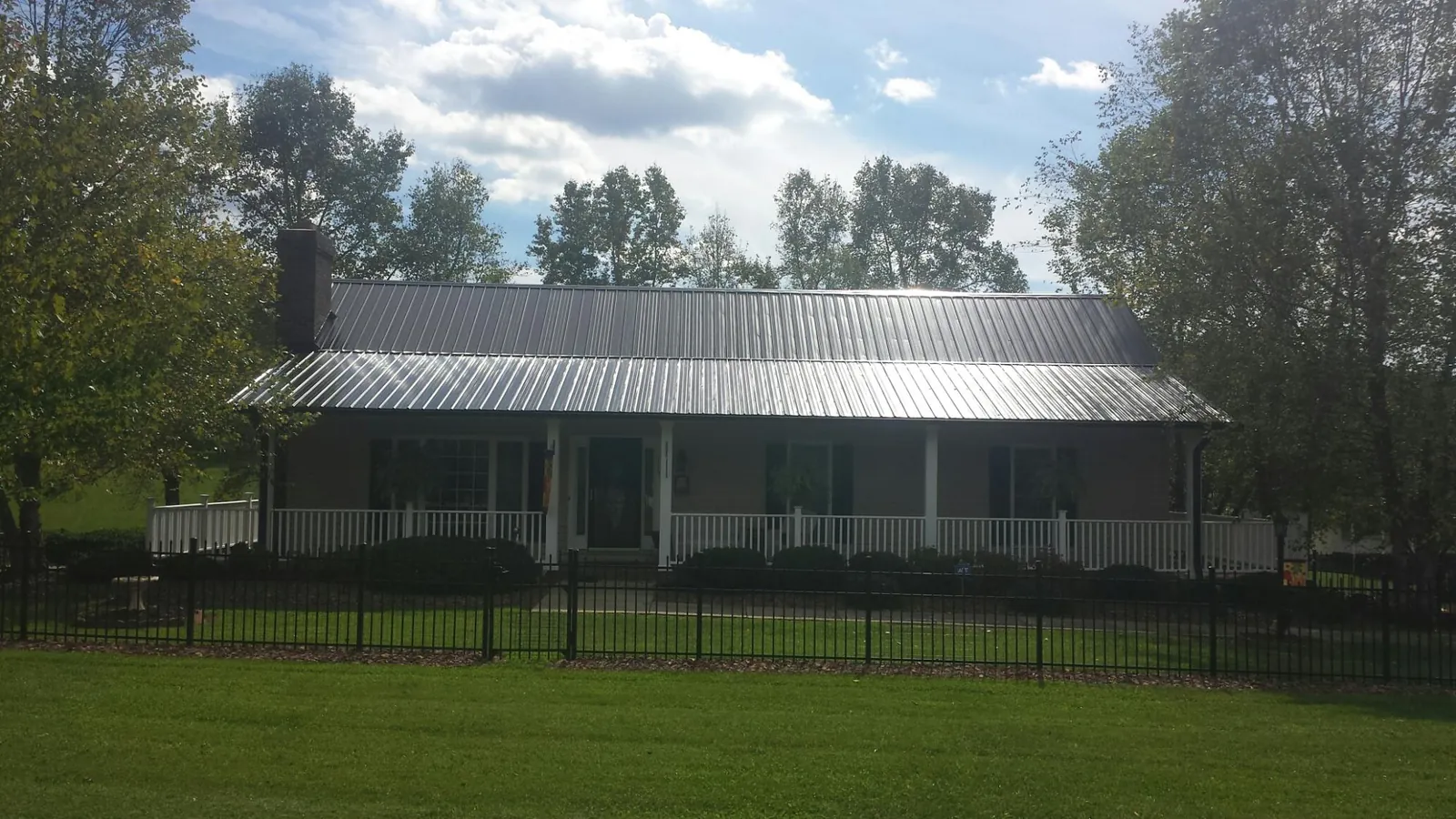 Gray metal roof on a brick ranch with a full width front porch — Gutter Guard Installation work by our crew in Lockwood