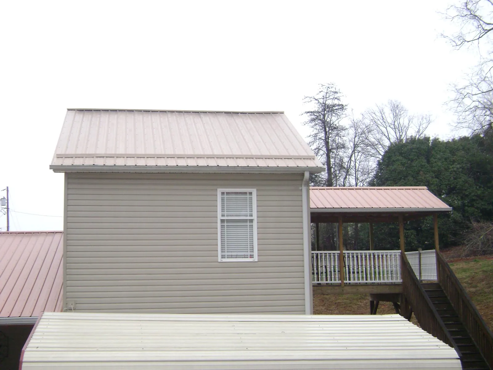 Tan metal roofs on a two story addition and attached porch, from a Roof Replacement job in Lockwood