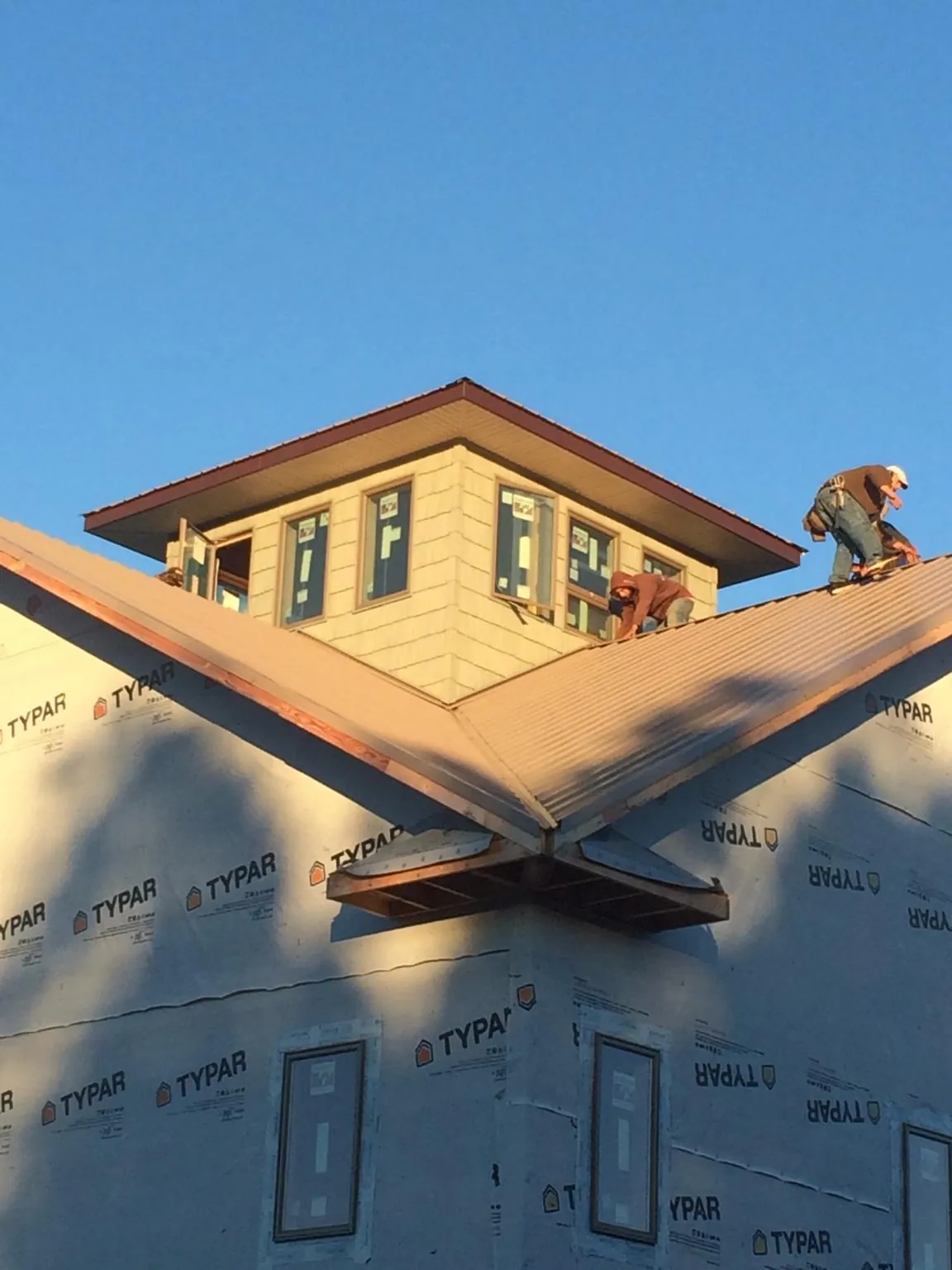 Roofers working around a rooftop cupola on a new metal roof at sunset — Roof Waterproofing in Lockwood by Roofing Brothers
